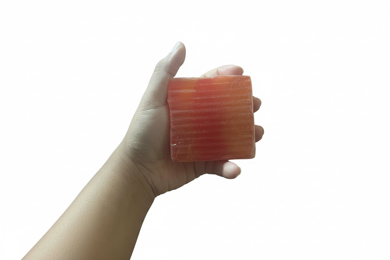 Hand Holding Yoni Bar Soap Showing Actual Size And Textured Surface Of The Red And Golden Cleansing Bar