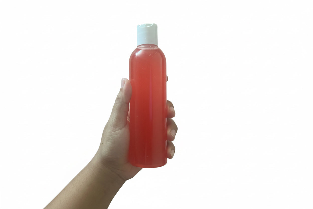 Hand Holding Yoni Shower Gel Bottle Showing Actual Size And Coral Formula Color